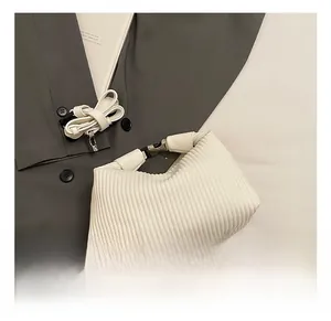 Détail du sac à main blanc plissé avec texture fine, boucle en métal et bandoulière