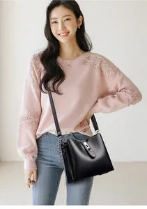 Sac seau en cuir noir à texture litchi avec fermoir en métal argenté porté