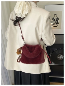 Detail of burgundy faux fur bag with leopard charm and sleek leather strap