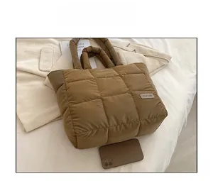 Detail of brown quilted puffer tote bag featuring a Fashion label and puffy texture