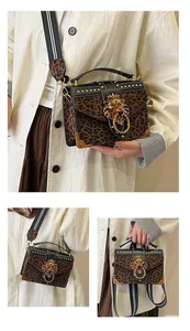 Detail of leopard print crossbody bag with gold lion head buckle and wide striped strap