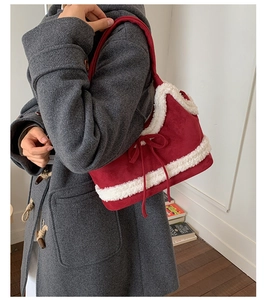 Detail of red suede shoulder bag with sherpa trim and bow accent for winter style