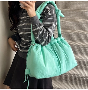 Close-up of mint green puffer bucket bag featuring quilted texture and knotted strap detail