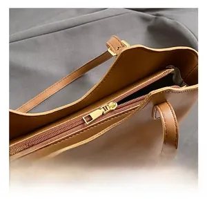 Close-up of brown leather tote bag with gold hardware and top zipper detail