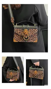Detail of leopard print handbag featuring a gold lion head buckle and studded leather trim