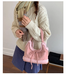 Pink faux shearling and suede bucket bag featuring a decorative bow tie and plush texture