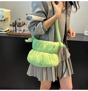 Detail of light green pleated cloud bag featuring soft padded texture and knotted shoulder strap