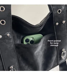 Detail view of the black canvas tote bag with metal rivets and functional front pocket