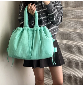 Detail of mint green quilted tote bag with drawstring texture and padded handle design