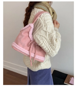 Detail of pink faux suede shoulder bag with soft fleece edges and a small ribbon bow