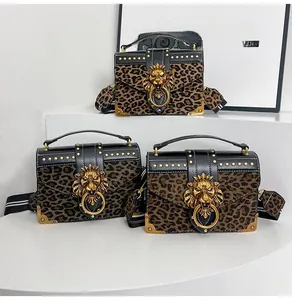 Detail of leopard print suede crossbody bag with gold lion head buckle and striped strap