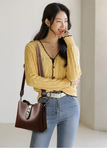 Détail du sac seau en cuir marron foncé avec fermoir rotatif en métal et bandoulière large