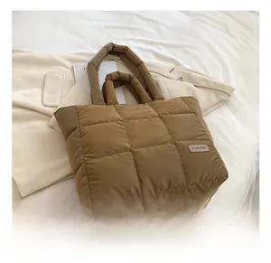 Detail of quilted puffer tote bag with brown fabric finish and fashion label patch