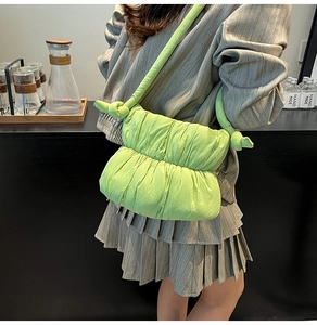 Detail of bright lime green cloud bag with pleated texture and decorative knot strap