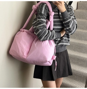 Detailed close-up of a pink quilted puffer bucket bag featuring a soft knotted shoulder strap