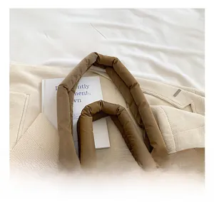 Detail showing the thick padded handles and quilted nylon texture of the brown tote bag