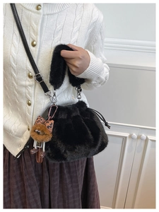 Close-up of black plush bucket bag with leopard print bear charm and leather strap