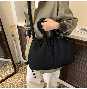 Detail of black puffy quilted tote bag with wide strap and ruched closure for daily use