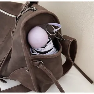 Detail view of the large capacity drawstring side pocket on a vintage brown leather bag