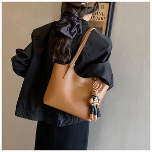 Brown leather tote bag with a cute rabbit plush charm and adjustable metal strap buckle