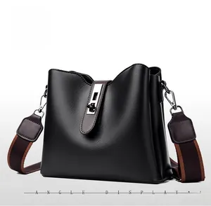 Vue latérale du sac seau en cuir grainé noir avec fermoir argenté et bandoulière rayée