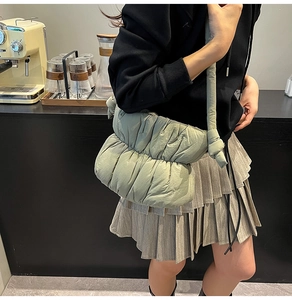 Close-up of a mint green quilted puffer shoulder bag with soft knot strap detail