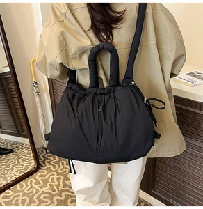 Back view of a model wearing a black padded bucket bag with a cozy cloud-like texture