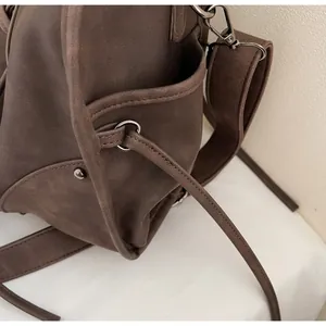 Detail of dark brown suede tote bag featuring side pocket and metallic ring hardware