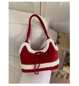 Detail of red suede shoulder bag with white fleece trim and decorative bow on white sofa