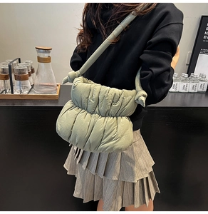 Detail of light green quilted cloud bag featuring side knot straps and gathered fabric