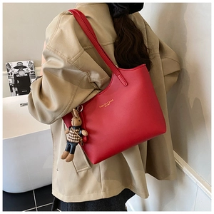 Detail of red leather tote bag with a golden brand stamp and a cute bunny doll charm