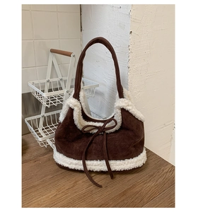 Detail of suede tote bag featuring fuzzy shearling trim and decorative bow accent