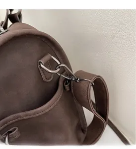 Detail of dark brown matte suede shoulder bag with gunmetal hardware studs and buckle