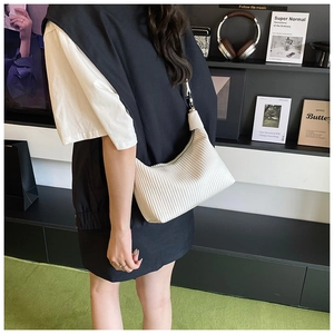 Détail du sac à bandoulière plissé blanc avec texture accordéon porté par un mannequin