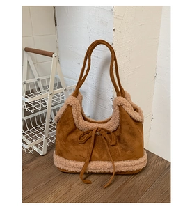 Brown suede tote bag with cream fleece trim and decorative bow detail shown in lifestyle setting