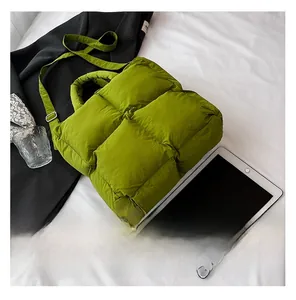 Detailed top view of a green puffer tote bag with quilted padding on a white background