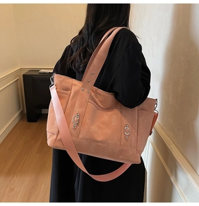 Detail of a large pink tote bag with wide crossbody strap and metal ring buckle