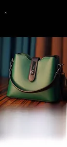 Détail du sac seau en cuir vert avec poignée marron et fermoir magnétique doré