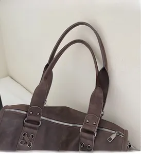 Detail of dark brown tote bag showing textured material and reinforced rivet handles