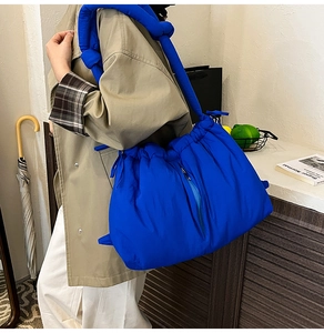 Detail of Klein blue padded bucket bag featuring a knot-style shoulder strap and puffy texture