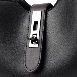 Détail du sac seau en cuir noir avec fermoir rotatif argenté et bandoulière marron foncé