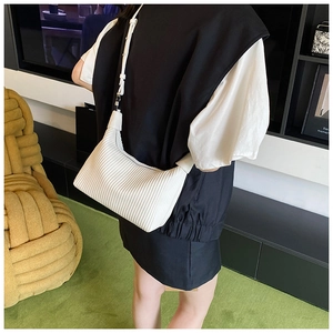 Détail d'un sac à bandoulière blanc plissé avec texture verticale sur un mannequin