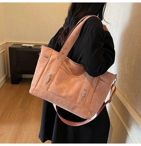 Detail view of pink tote bag showing the textured material and metallic buckle accents