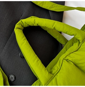 Detail of green quilted puffer tote bag with soft pleated texture and padded handle