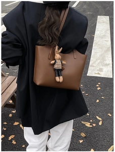 Close-up of a dark brown faux leather tote bag with a cute brown rabbit plush charm