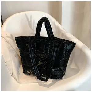 Close-up of quilted black puffer tote bag with glossy finish and fashion logo patch