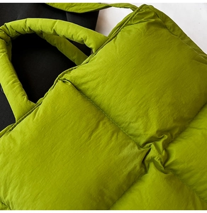 Detailed macro view of vibrant green quilted nylon puffer tote bag with padded handles