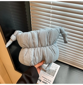 Detail of light blue puffer cloud bag with large side knots and soft padded handle