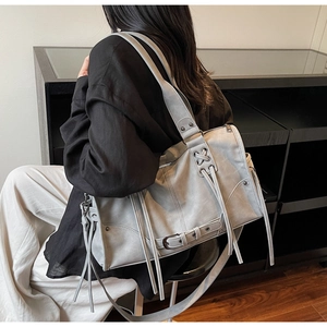 Detailed view of grey leather tote bag with fringe tassels and wide shoulder strap