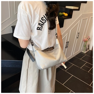 Détail du sac croissant argenté avec texture plissée verticale porté à l'épaule